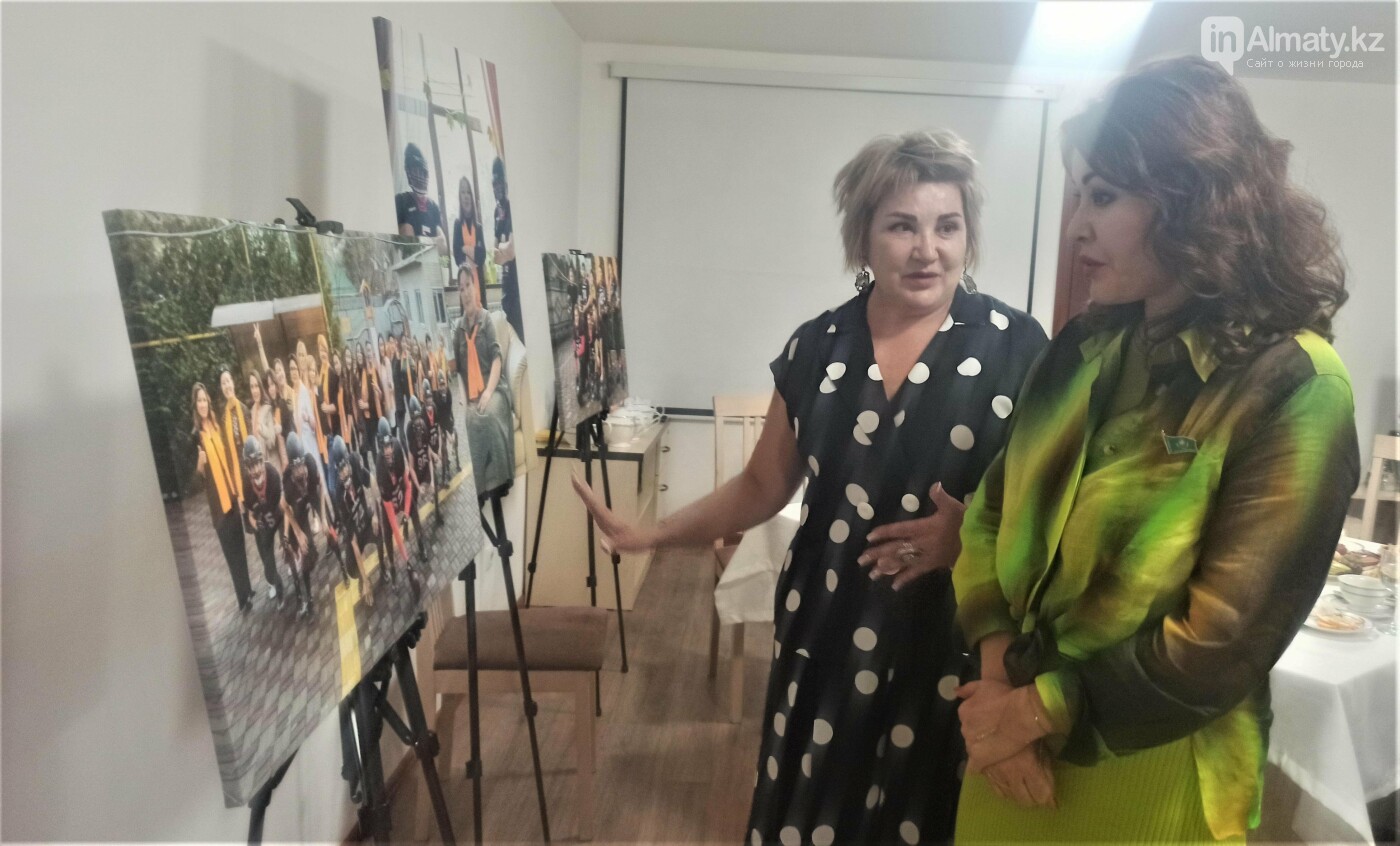 Зульфия Байсакова показывает гостям центра фотографии социального проекта в поддержку женщин